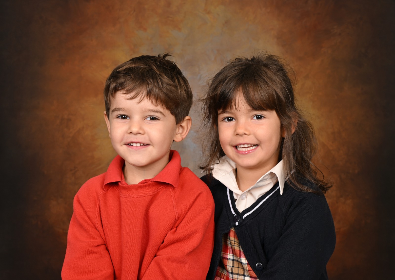 Two students in school uniform smiling together for a traditional sibling portrait