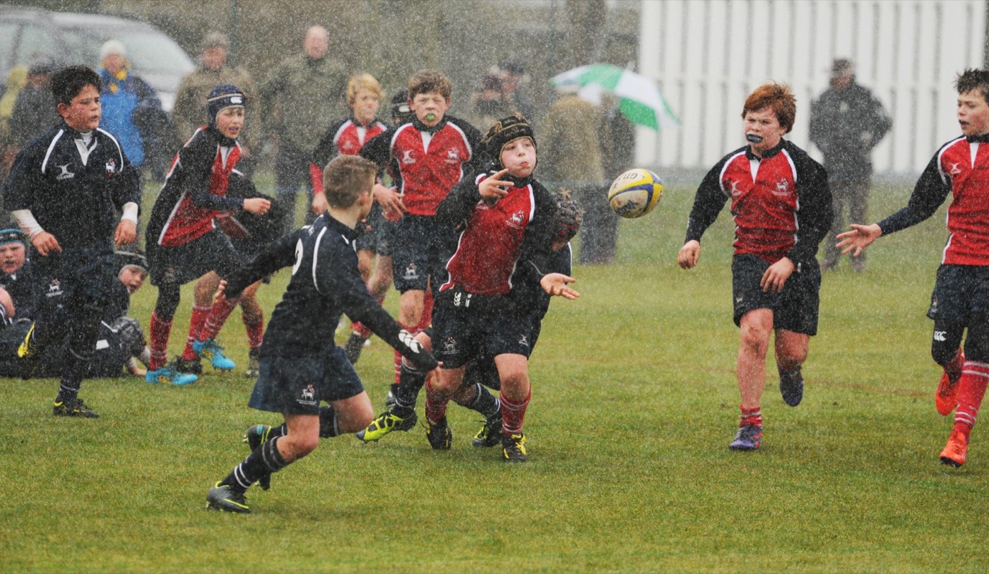 Students in the rain during a school rugby match